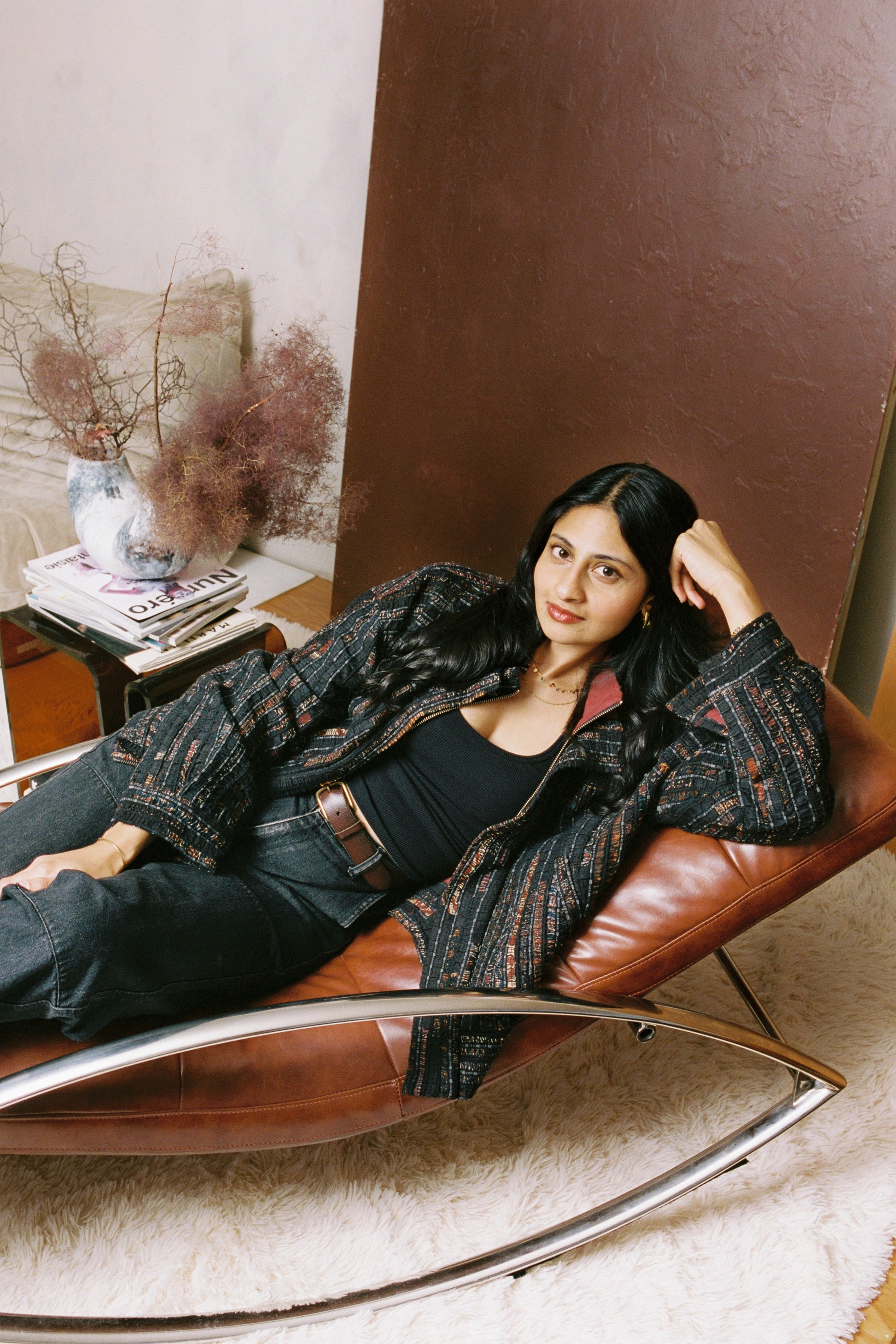 Model comfortable at home wearing the Qaim Sherry Bomber - structured, but relaxed fit, with Ajrak-inspired and burgandy red inner lining peeking through.