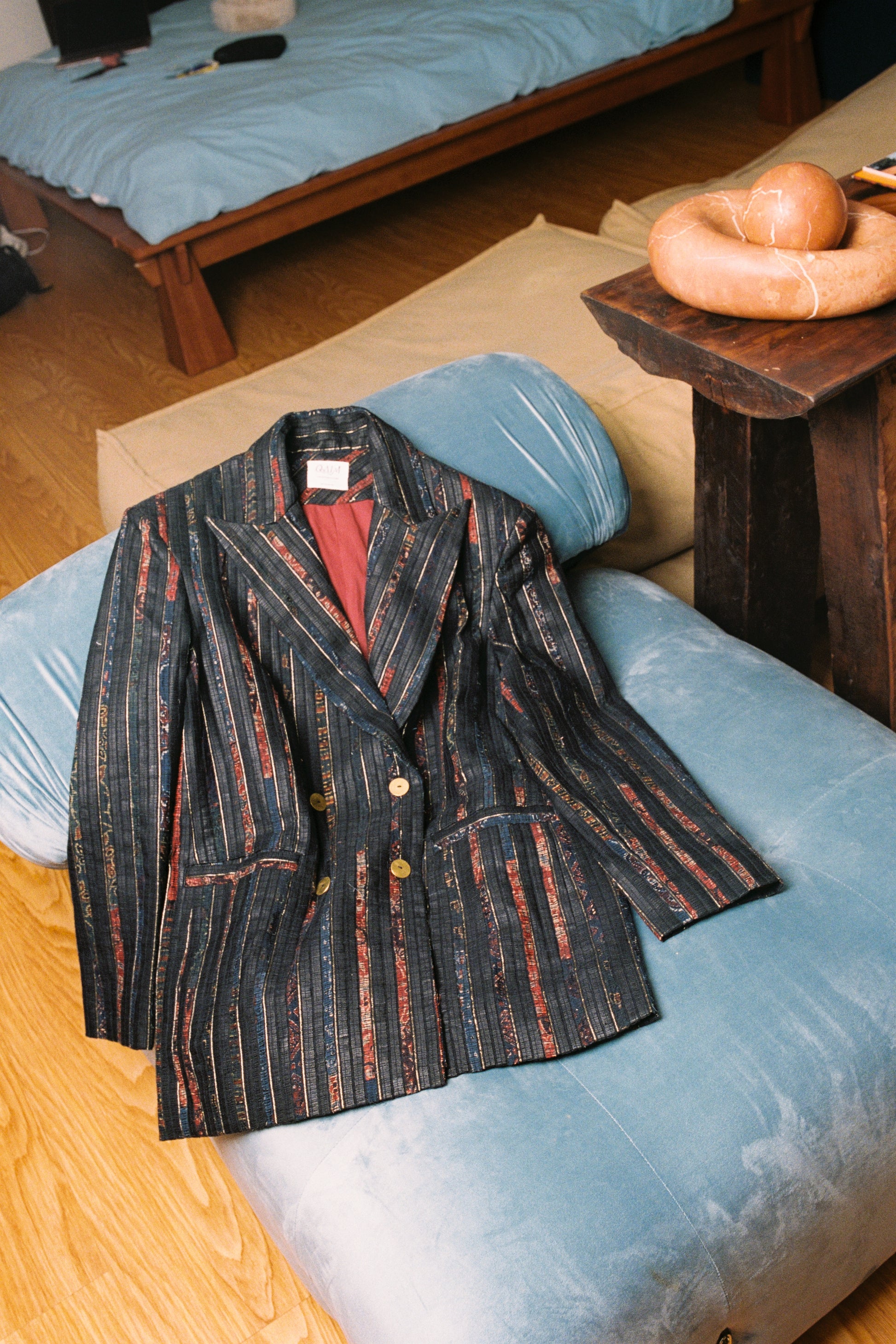 Striped jacket on a blue cushion with a wooden floor and furniture in the background