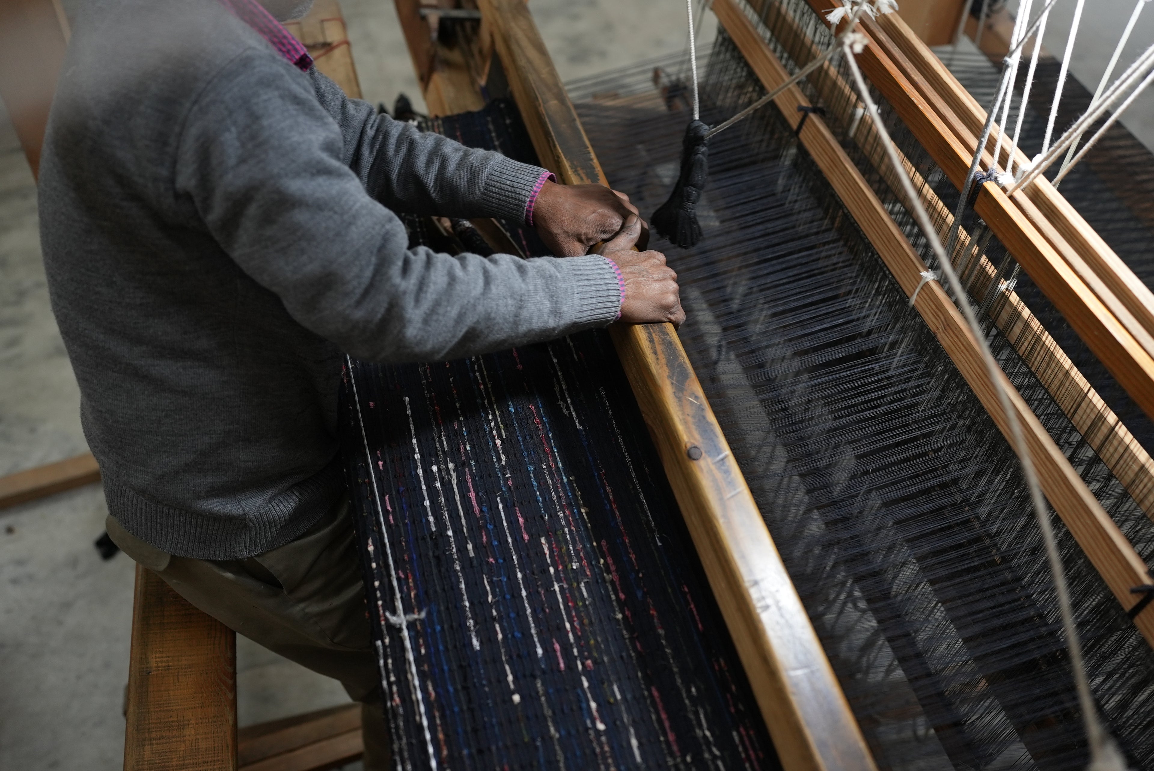 Artisan in India handweaving fabric using traditional techniques
