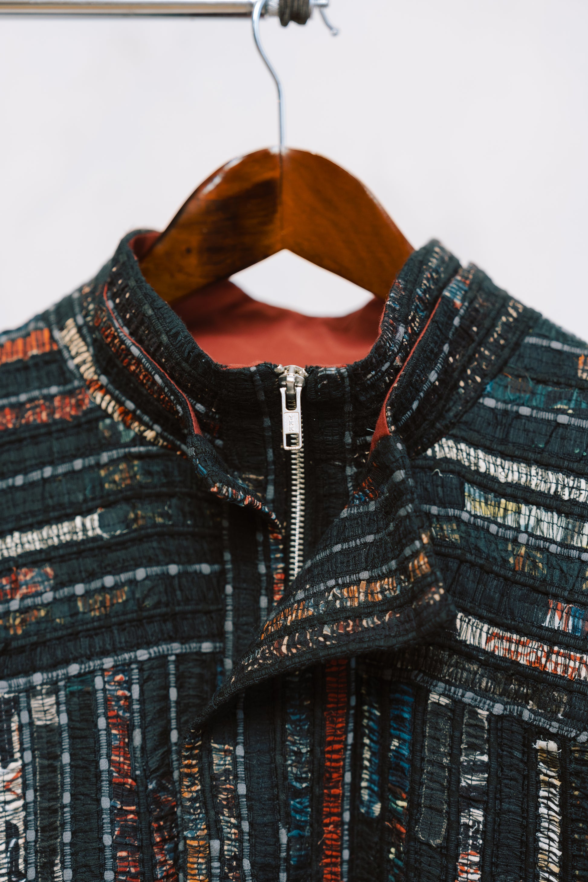 Qaim’s Sherry Bomber hanging against a neutral background to show details. Showcasing double collar and zipper with modern street style silhouette, zip closure, and subtle inner lining detail.