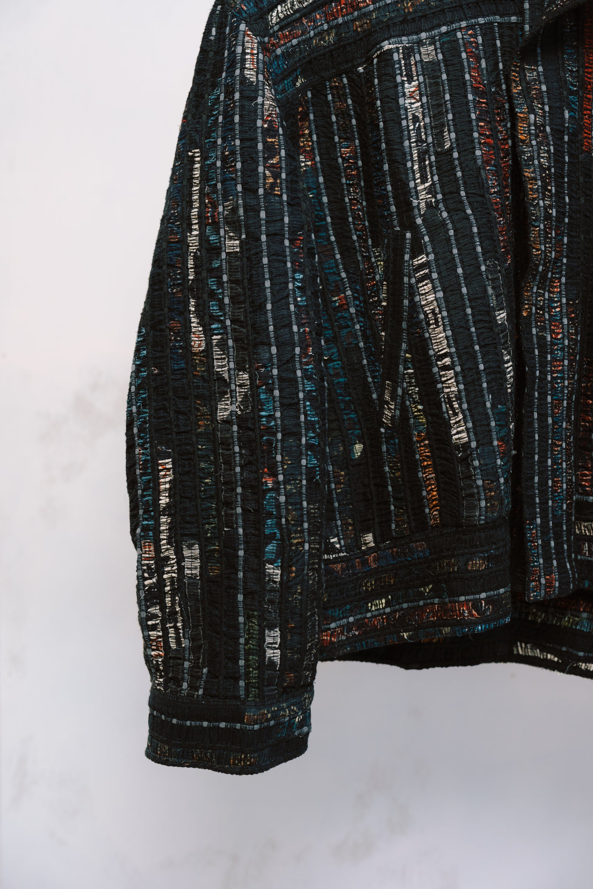 Qaim’s Sherry Bomber sleeve and pocket detail hanging against a neutral background to show details. modern street style silhouette, zip closure, and subtle inner lining detail.