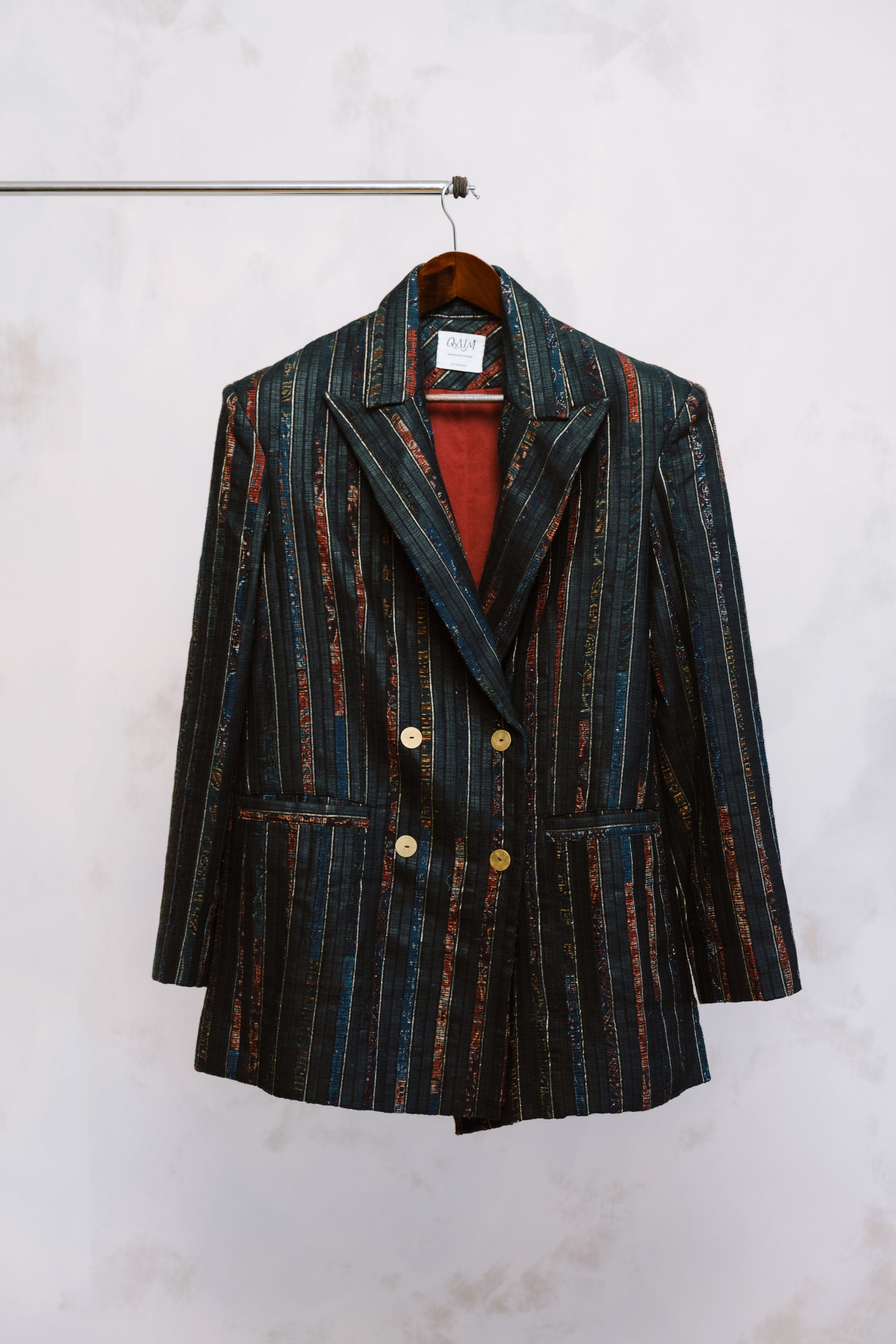 Striped blazer on a hanger against a white wall