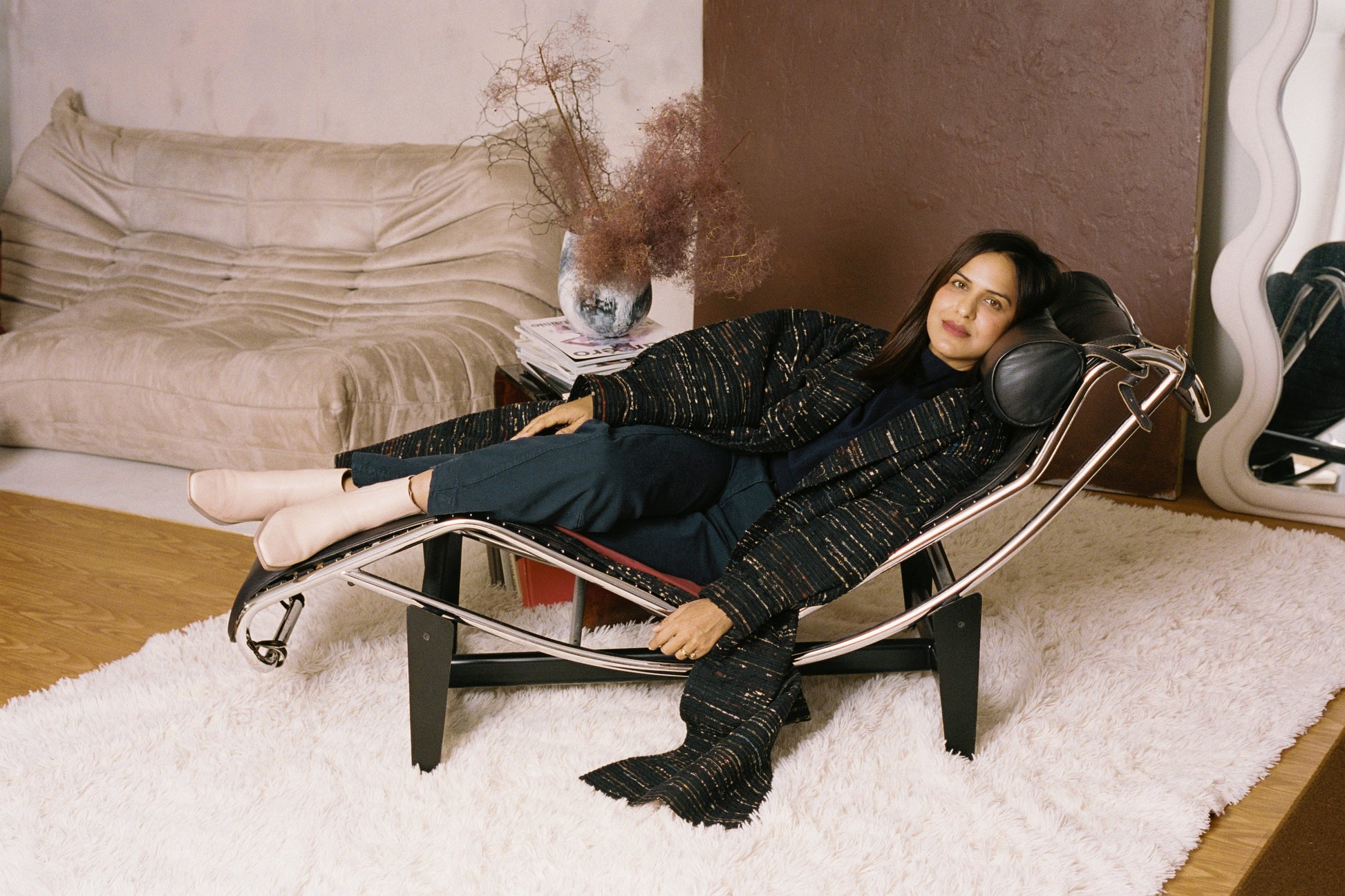 Woman lounging on a modern chair in a stylish room with decor elements.