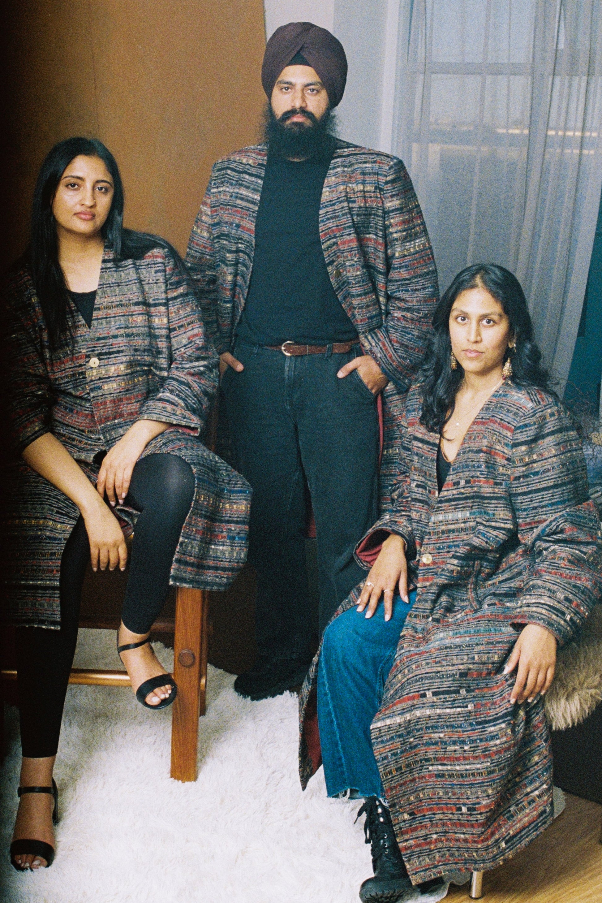 Models wearing the Ash Coat - a structured grey overcoat featuring bold shoulders and ajrak fabric accents, designed for both professional and creative settings.