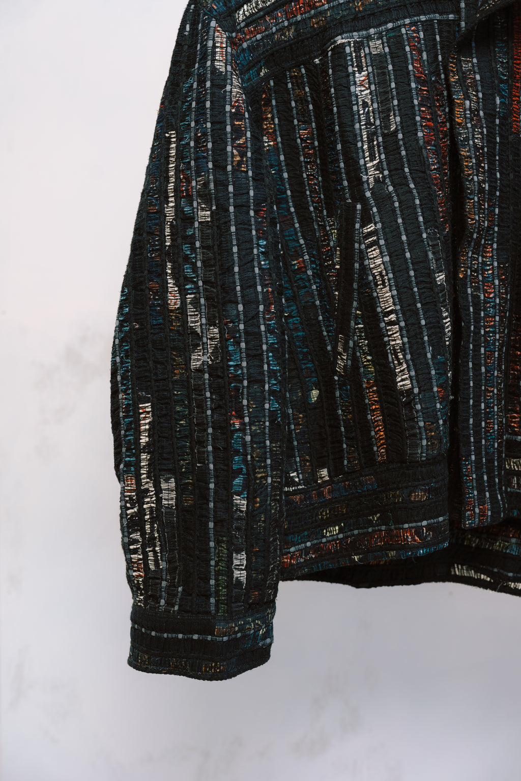 Qaim’s Sherry Bomber sleeve and pocket detail hanging against a neutral background to show details. modern street style silhouette, zip closure, and subtle inner lining detail.