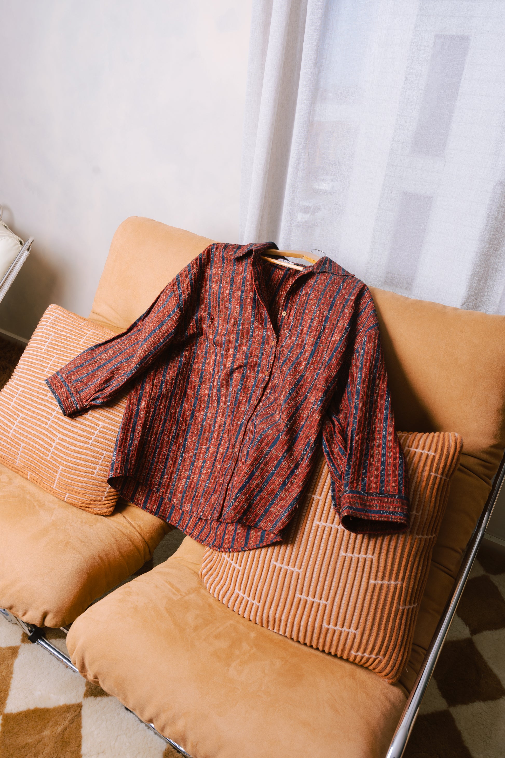 Unisex red overshirt in modern studio, featuring traditional Sindhi Ajrak detailing.