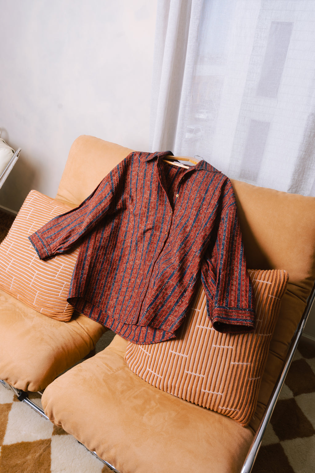 Unisex red overshirt in modern studio, featuring traditional Sindhi Ajrak detailing.